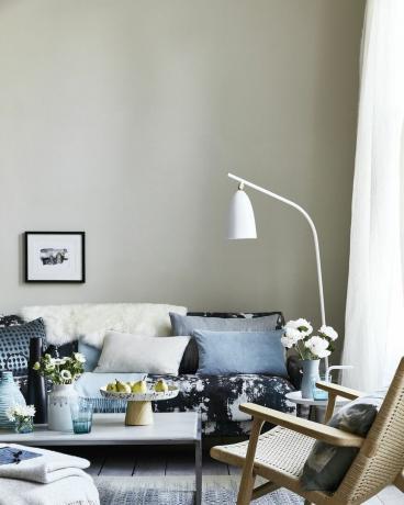 neutrálna obývačka, obývacia izba s vankúšmi na pohovke s modrým vzorom, ohýbaná biela stojaca lampa na pohovke kvapká, škvrny a striekané vzory pre animpresionistický vzhľad, ktorý je súčasný a uvoľnený