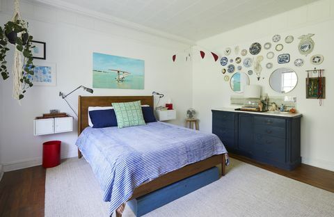 dormitorio principal, ropa de cama azul, armazón de cama de madera, gabinetes azules, pared de la galería, placas colgantes