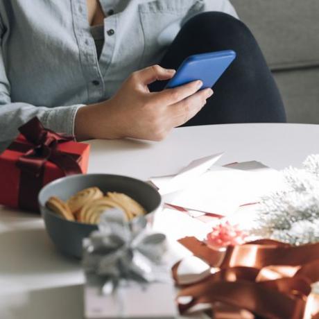 Noel ortamında mesaj göndermek için akıllı telefonunu kullanan bir kadının yakın çekimi