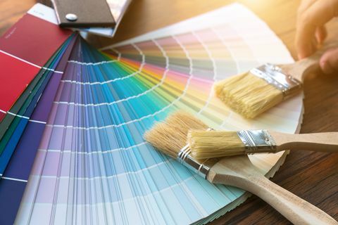 Table de travail pour peintre et décorateur avec projet de maison, échantillons de couleurs, rouleau à peinture et pinceaux