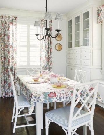 नाश्ता कक्ष, सफेद डाइनिंग चेयर, सफेद और नीले रंग की धारीदार कुर्सी कुशन, सफेद भंडारण, फूलों के पर्दे और टेबल टॉप