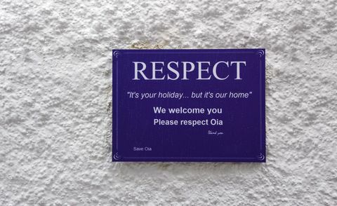 Znak uliczny na ulicach Santorini proszący turystów o zachowanie szacunku