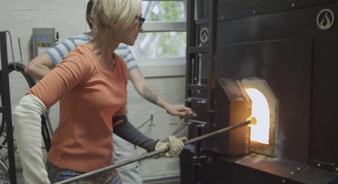 cheryl saban įdeda stiklo gabalėlį, prie kurio ji dirba, į šildytuvą gamybos proceso metu