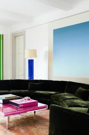 moderne woonkamer met roze salontafel, groene bank en blauwe kunst