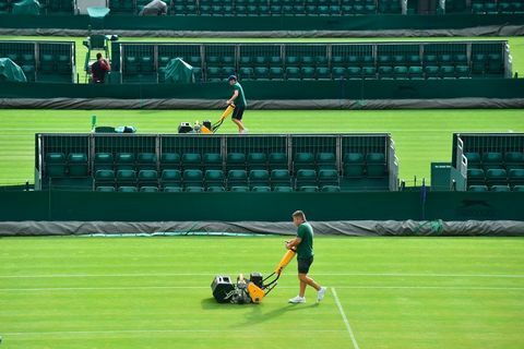 A equipe de campo corta a grama em uma quadra do The All England Lawn Tennis Club em Wimbledon