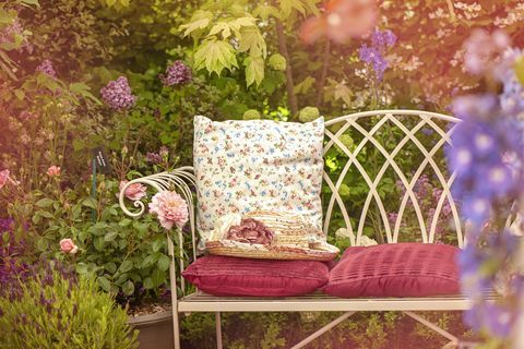 방석과 여름 모자가 있는 아름다운 여름 주철 정원 의자, 초라한 세련된 장면