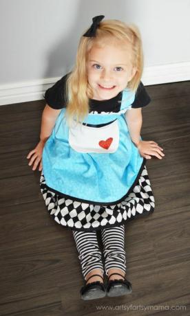 малко момиченце, облечено като Алиса в страната на чудесата в рокля на предната част