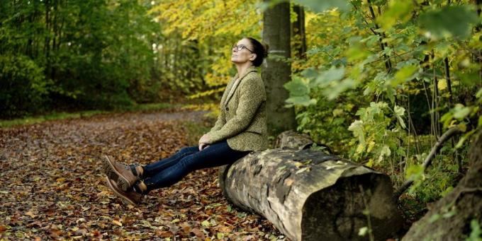 volwassen vrouw zittend op een boomstam in een herfstbos