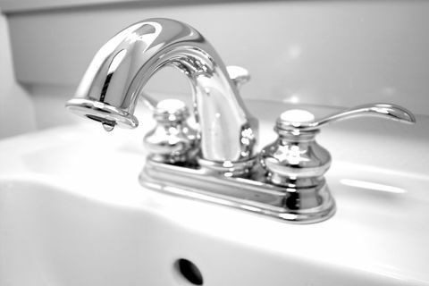 fotografie alb-negru cu cheie înaltă a unui robinet cromat care curge