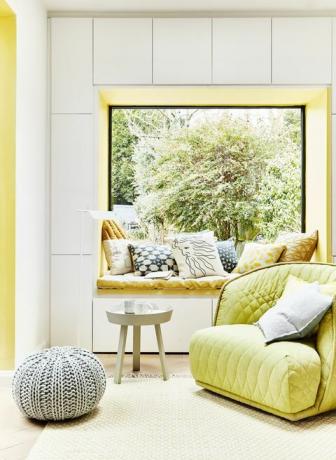 grüner gelber Sessel, der mit Kissen bedeckt ist, die an einem Fenster platziert sind, lassen Sie die Nischenwand eines Fensters ausstreichen oder Fensterplatz ist eine großartige Möglichkeit, um einen Akzent in ein Schema zu bringen, das mit einer vielseitigen Mischung aus Mustern koordiniert wird Kissen