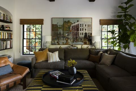 居間、緑のソファ、革張りの椅子、黄色い枕、白い壁