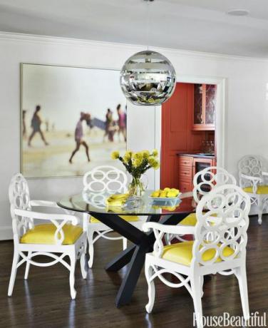 Vintage stoličky Frances Elkins s citrónovo žltými vinylovými sedadlami rozjasňujú raňajkovú miestnosť. Malebná tlač od Thoma Filiciu visí na stene namaľovanej v Šedej sove Benjamina Moora. Zebra prívesok od Y Lighting. Komora komorníka je lakovaná oranžovou farbou, Žirafa Benjamina Moora, ktorá odráža odtieň tapety v jedálni.