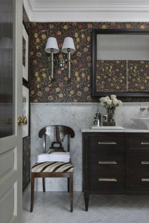 łazienka, drewniane szafki, marmurowe kafelki na podłodze i ścianach, kwiatowe tapety, kinkiety
