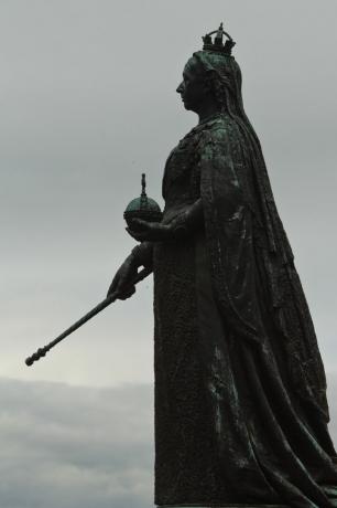 karalienes Viktorijas statuja pret debesīm