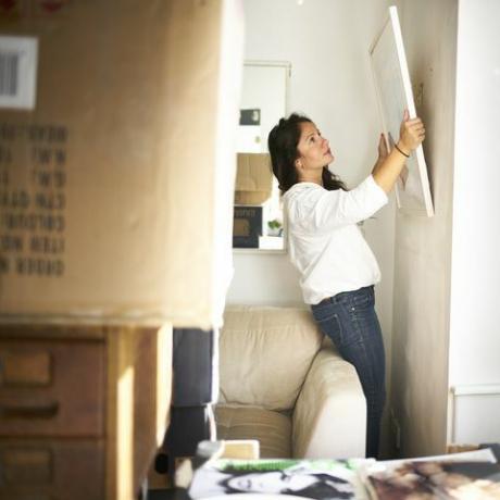 Женщина делает снимок со стены, готовый упаковать вещи во время переезда