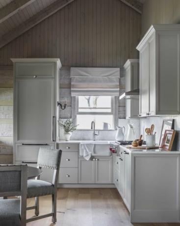 ნაცრისფერი სამზარეულოს კარადები, თეთრი წყლის დოქები, ჩარჩოში ჩასმული ხელოვნების ნიმუშები, ნაცრისფერი სასადილო სკამები