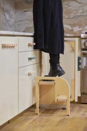 una persona alcanzando gabinetes más altos en un taburete