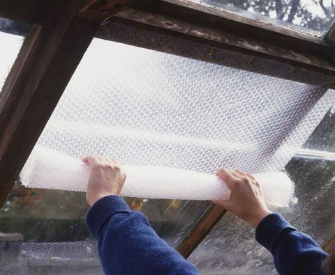 Pár kezét buborékfóliát helyezve az üvegház ablakára